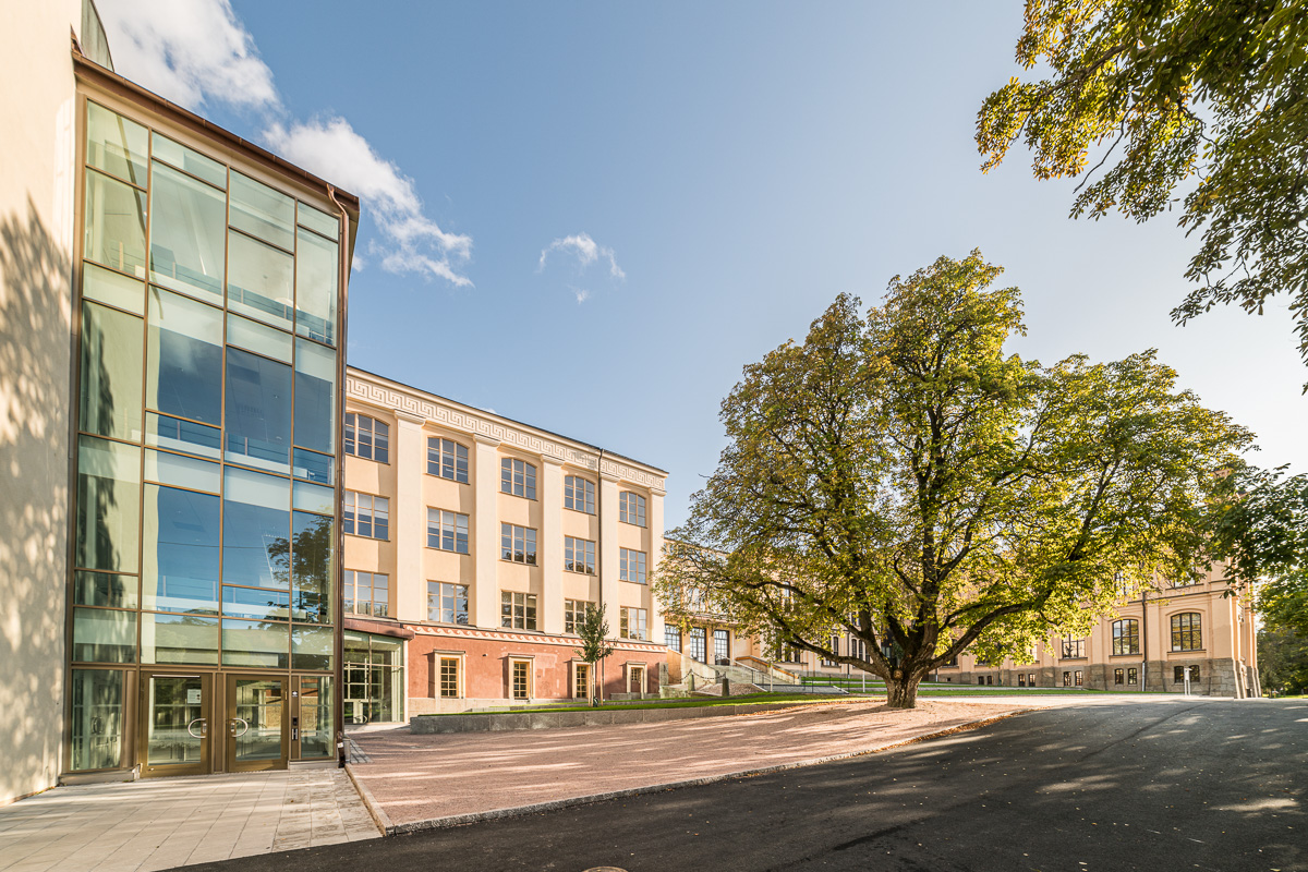 Skolgård med träd framför en fin 1800-tals skola.