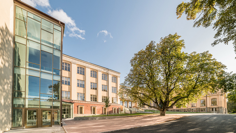 Skolgård med träd framför en fin 1800-tals skola.