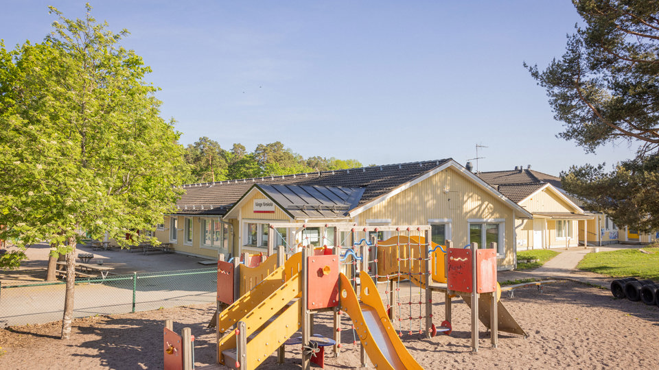 Klätterställning framför en förskola i gult trä.