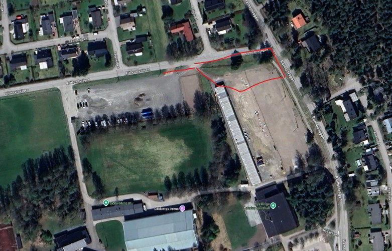 Satellitbild som visar en inringad yta på en grusplan vid en skola.