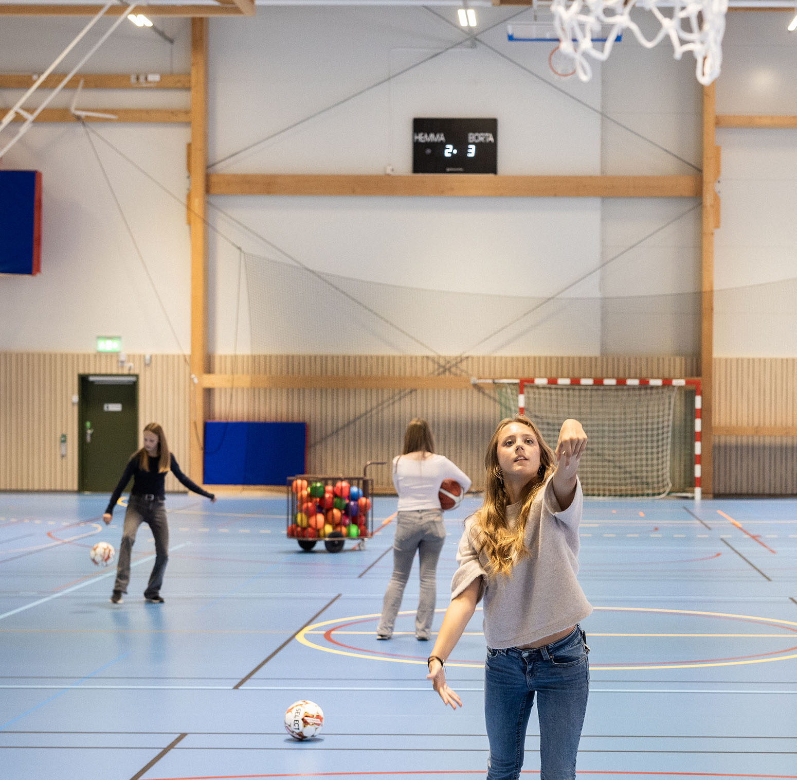 Flicka kastar en basketboll i en idrottshall.