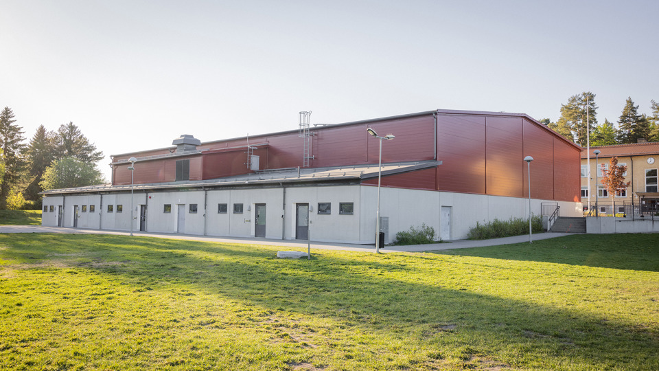 Röd idrottshall med grönt gräs i förgrunden
