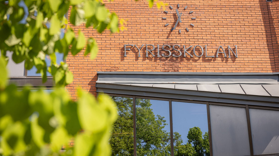Fasad i brunt tegel med skolskylt