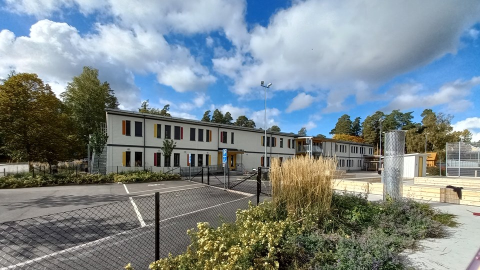 Framsidan av Rosendals modulskola med parkering och delar av skolgård