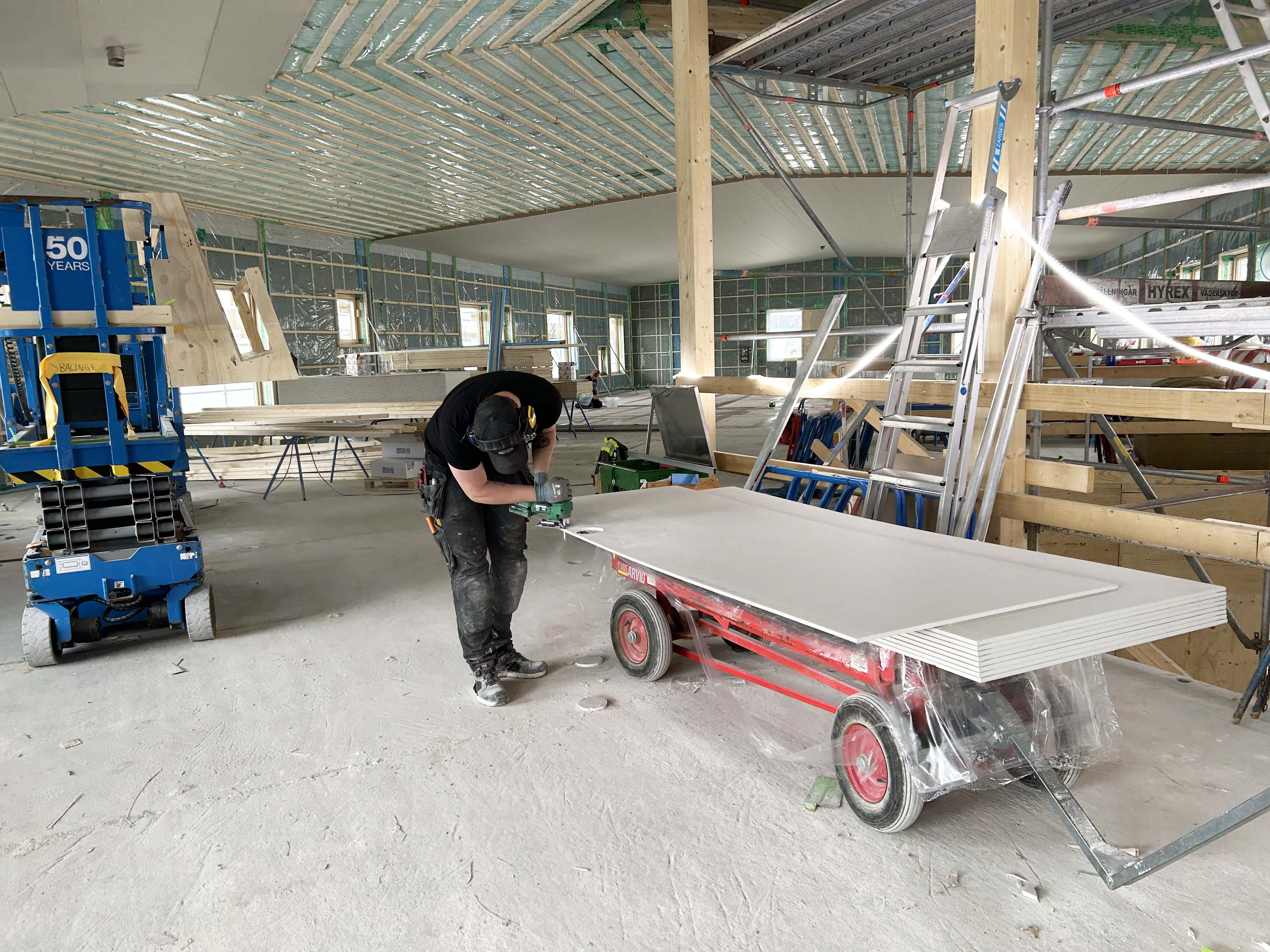 Byggplats där en man arbetar med en vägg, inuti en blivande förskola.