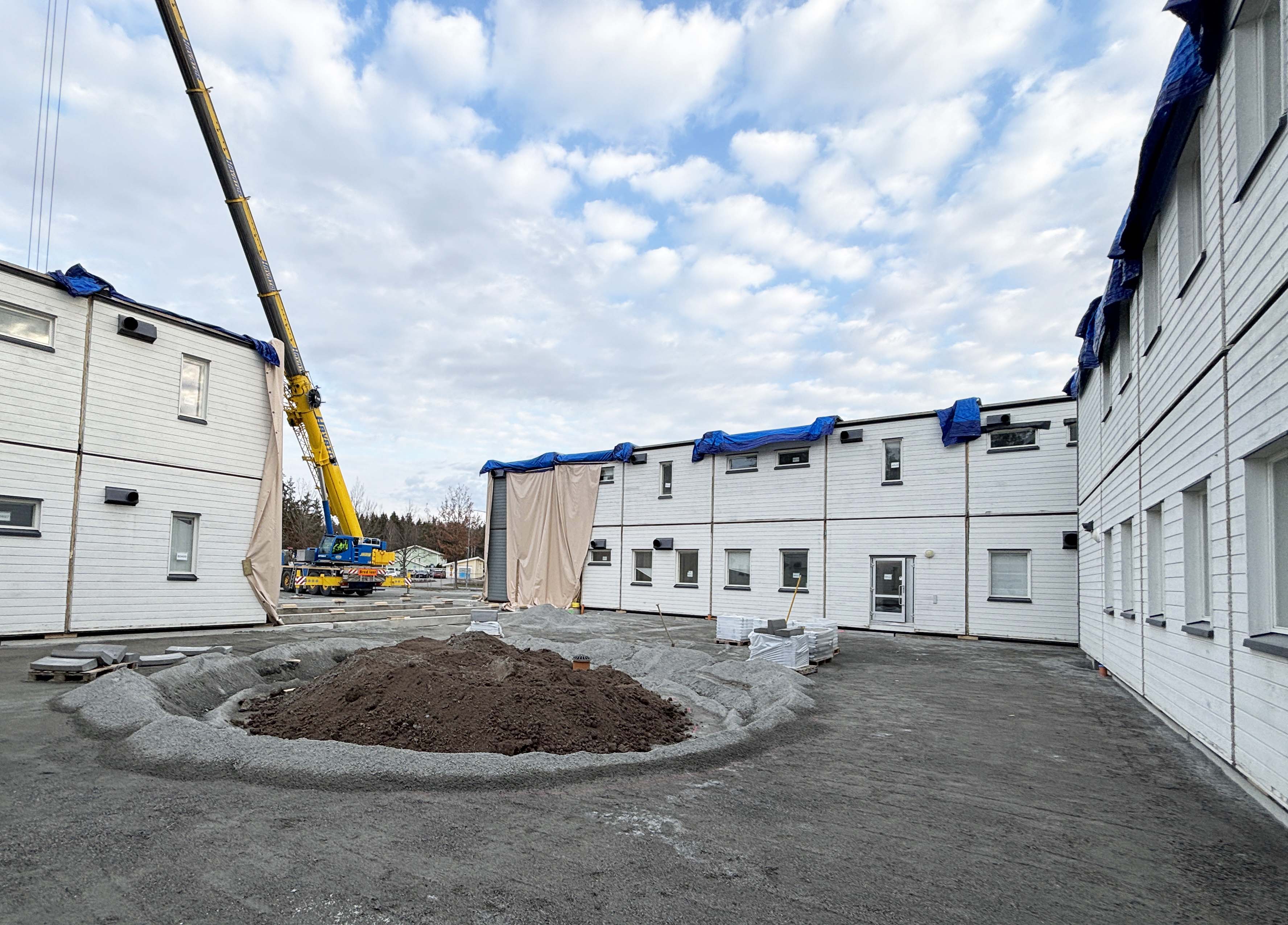 Byggnation av en modulskola med en gul lyftkran i bakgrunden.