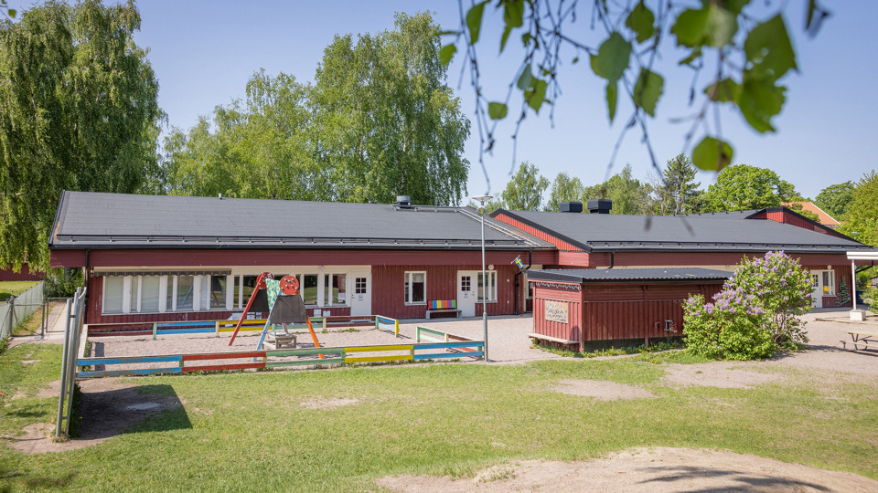 Röd förskola med gungställning i förgrunden
