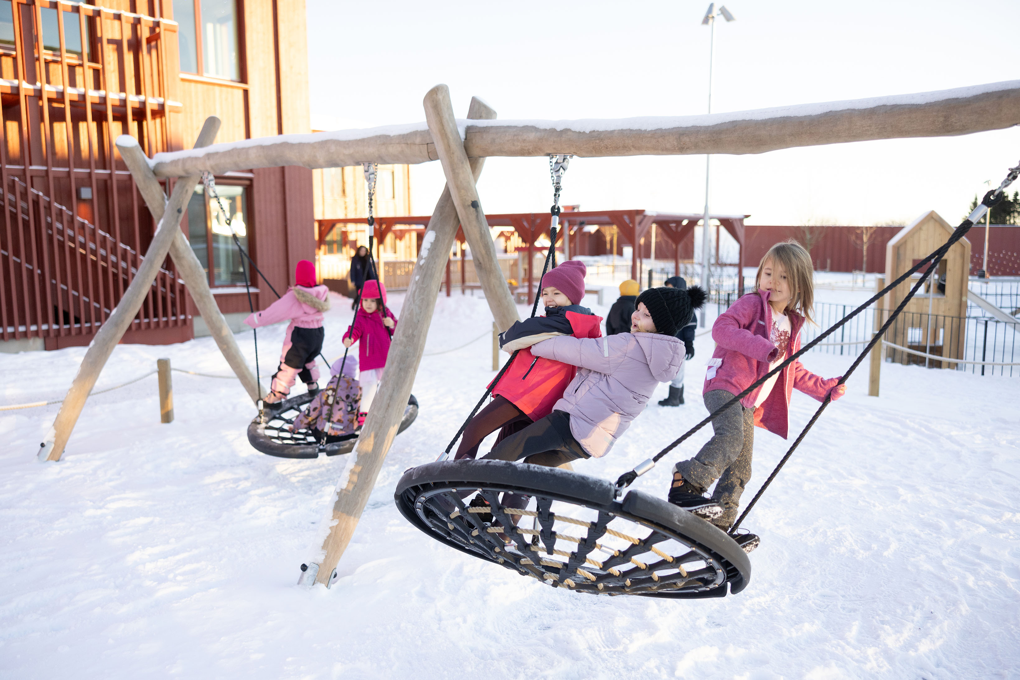 Barn som gungar på snöig skolgård.