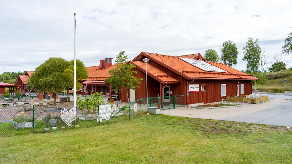 Överblick av Almunge förskolas skolgård och röda byggnad