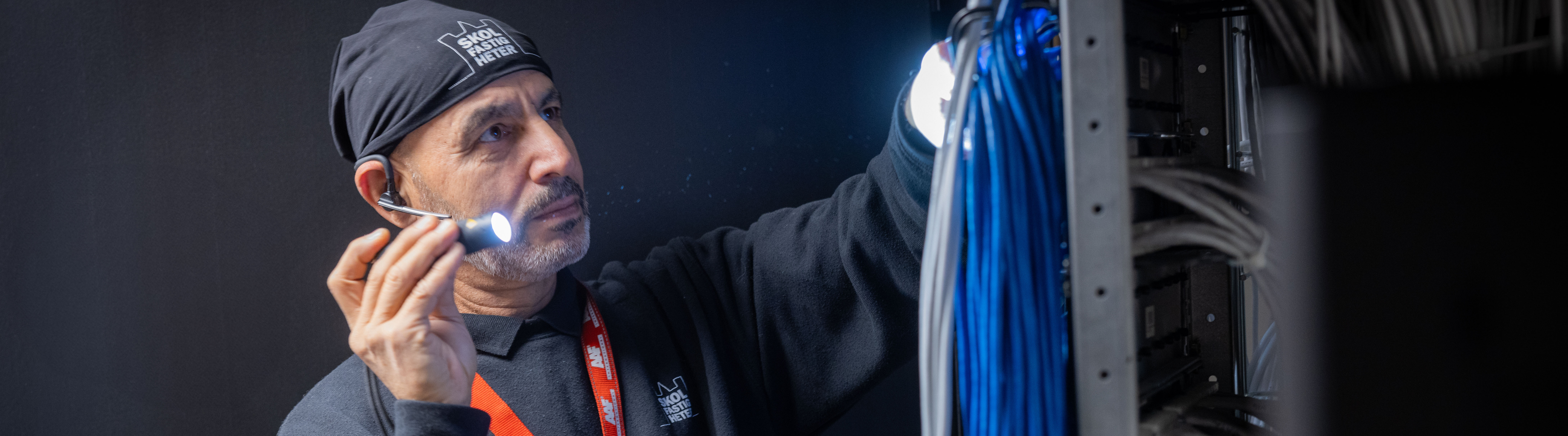 Drifttekniker med ficklampa vid elcentral 