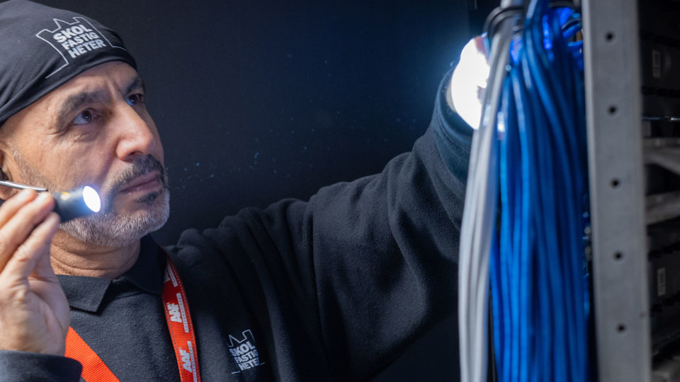 Drifttekniker med ficklampa vid elcentral 